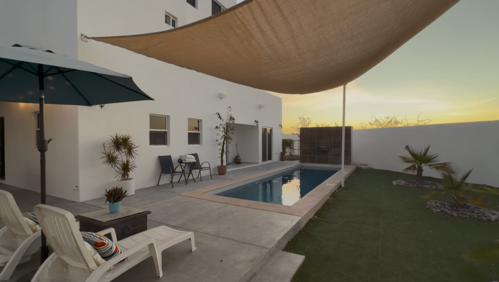 Pool courtyard at dusk with shade sail and lawn