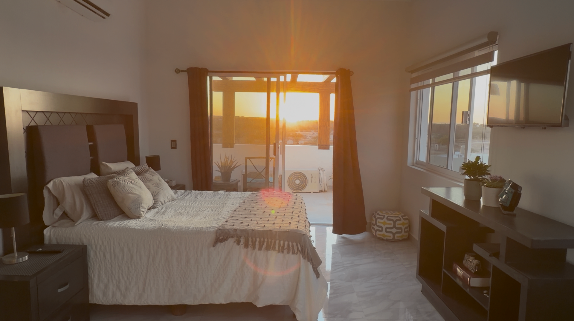 Bedroom at Casa Claudia opening onto a private west-facing balcony at sunset